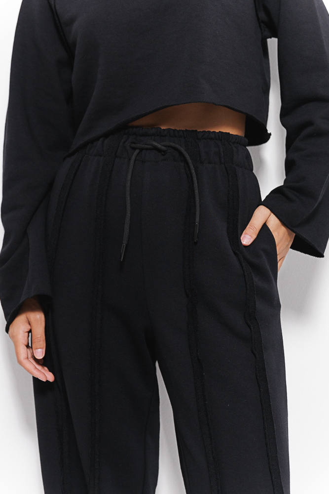 Women's black tracksuit with inside-out seams.