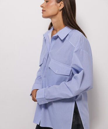 Women's shirt with chest pockets in milk color with blue stripes.