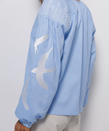 Women's blue embroidered shirt with swallows in satin stitch.